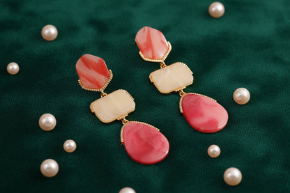 Pair of earrings with pink and beige stones on a beige background
