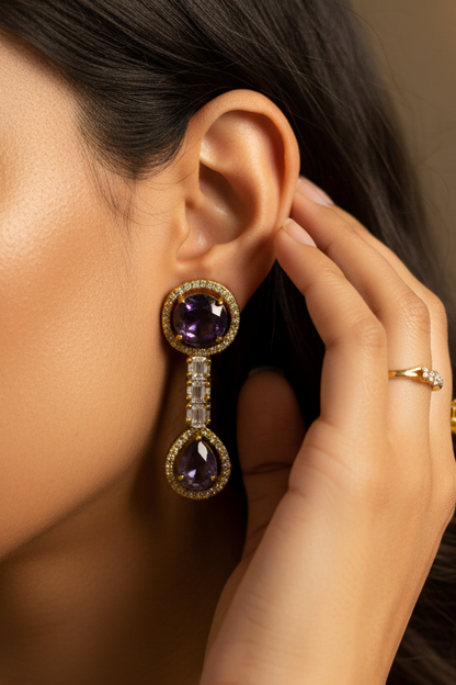 Gold-toned traditional jewelry set featuring a necklace and matching earrings with dark purple round stones, displayed on a cream-colored jewelry bust.