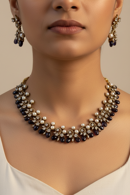 A gold-plated statement necklace and matching drop earrings displayed on a beige jewelry bust. The jewelry features white faux pearls, dark brown faceted beads, and clear rhinestones.