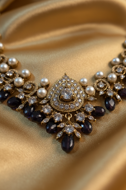 A gold-plated statement necklace and matching drop earrings displayed on a beige jewelry bust. The jewelry features white faux pearls, dark brown faceted beads, and clear rhinestones.