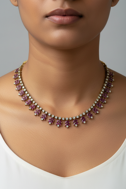 Gold-plated jewelry set featuring a necklace and matching drop earrings with deep purple gemstone floral motifs, displayed on a textured white jewelry bust.