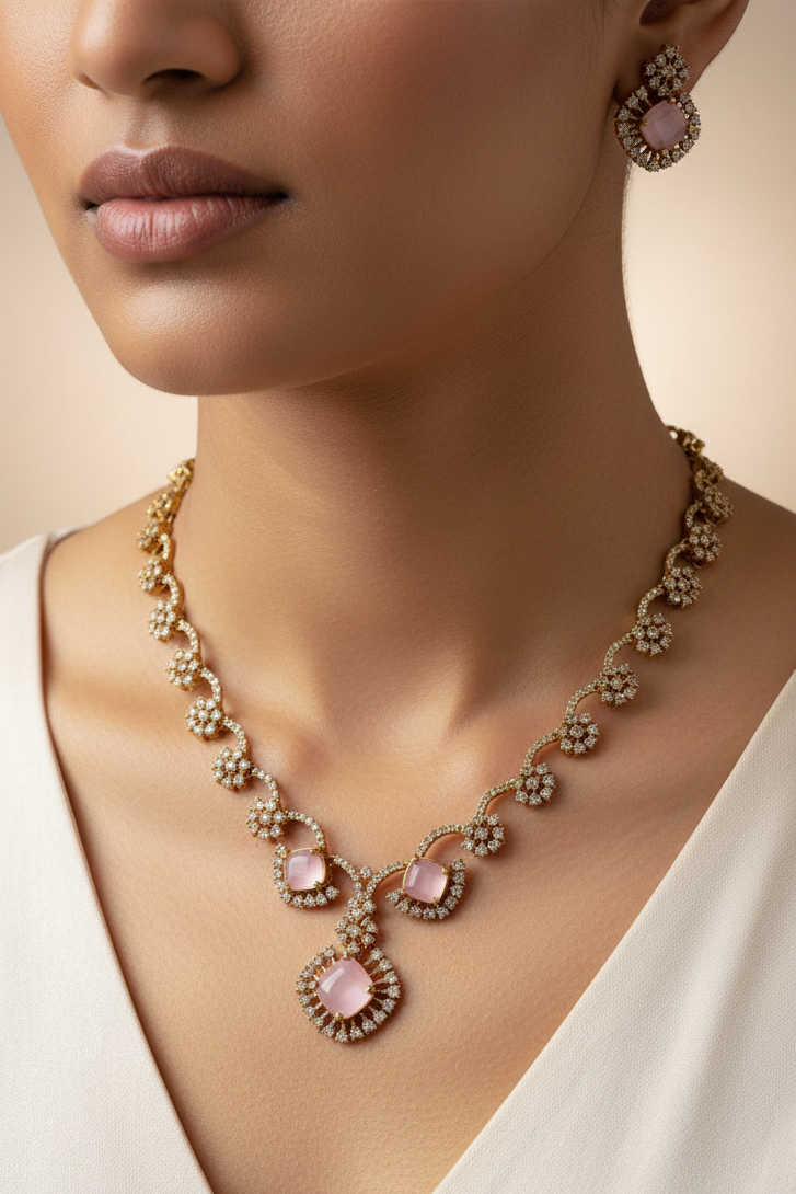 An ornate gold-toned jewelry set displayed on a white mannequin bust, featuring a necklace with pink stones and a matching top piece, set against a light-colored indoor background.